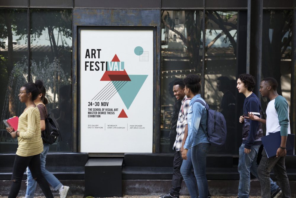 Group of diverse friends walking pass art exhibition placard